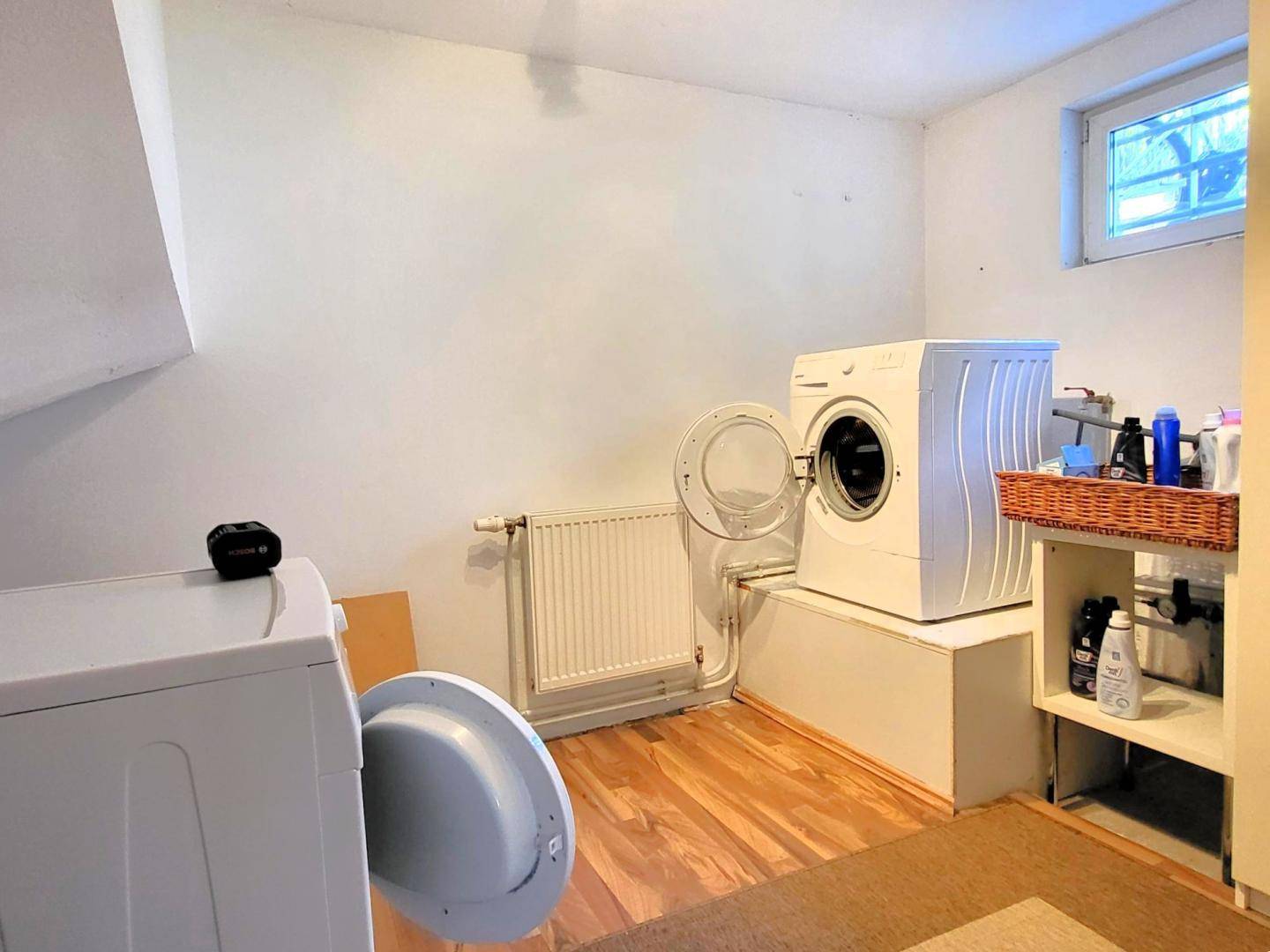Praktischer Hauswirtschaftsraum mit Waschmaschinen und Fenster für Belüftung.