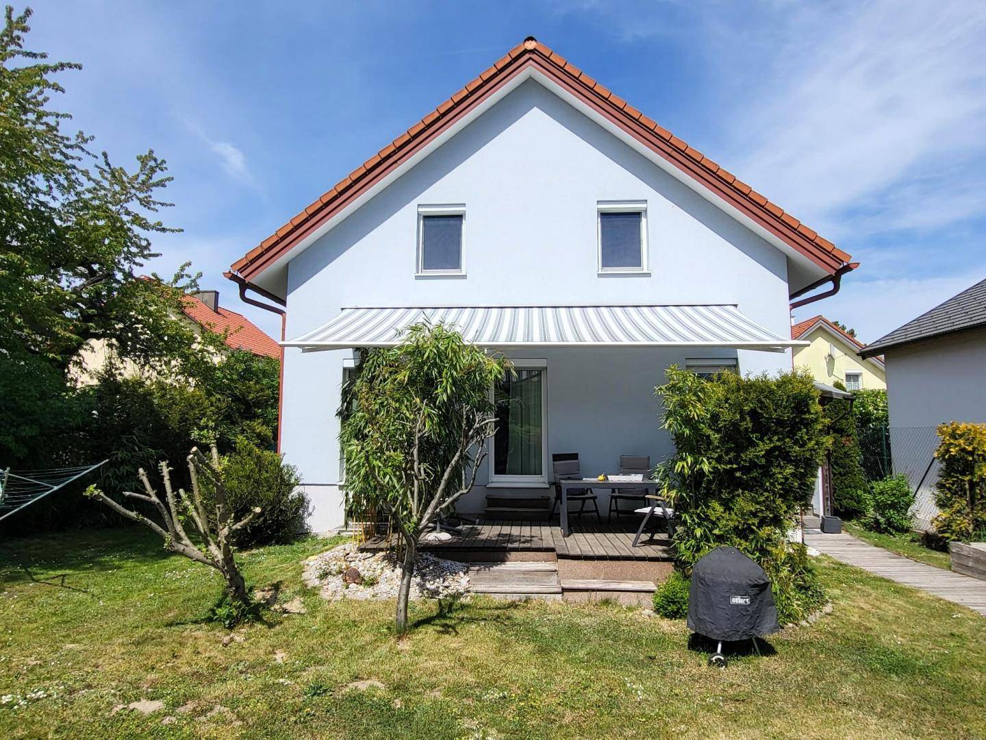 Rückansicht des Hauses mit Terrasse, Markise und einem gepflegten Gartenbereich.