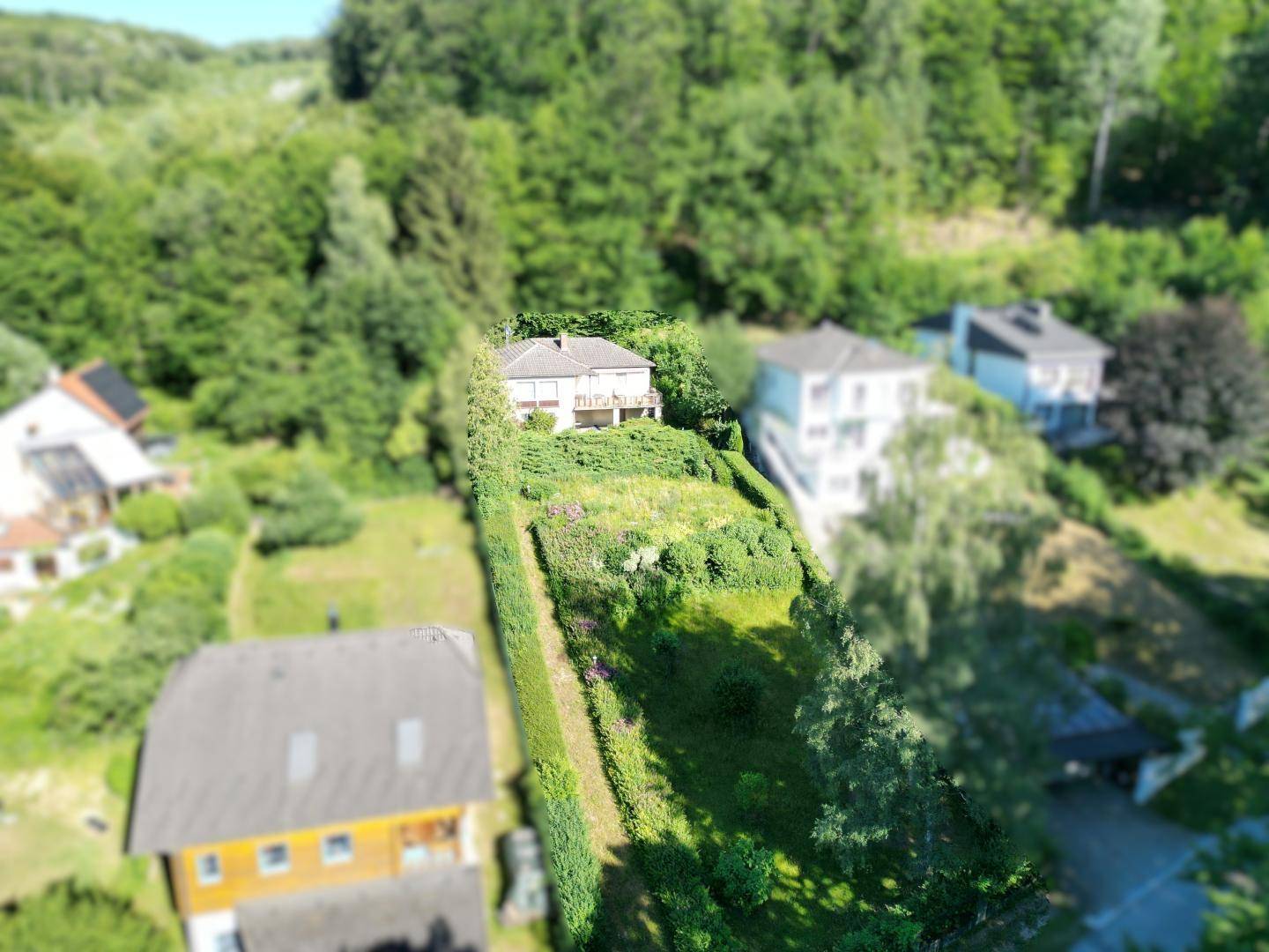 Luftaufnahme des Hauses in einer grünen, hügeligen Landschaft mit weiteren Gebäuden.