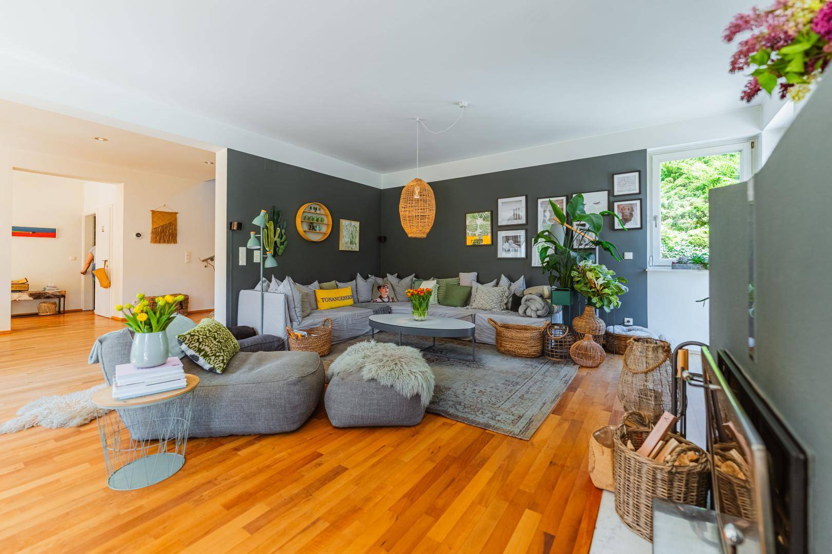 Gemütliches Wohnzimmer mit stilvoller Dekoration, Holzboden und Blick ins Grüne durch das Fenster.