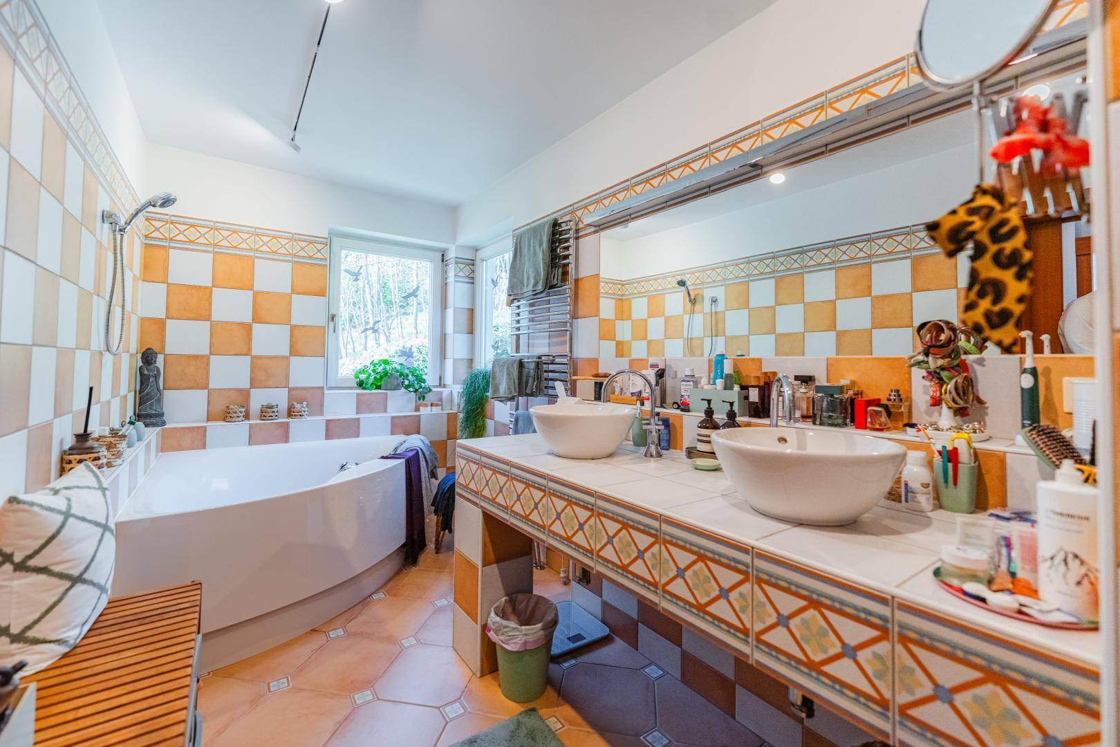 Badezimmer mit auffälligen orange-weißen Fliesen, Eckbadewanne und Doppelwaschbecken.
