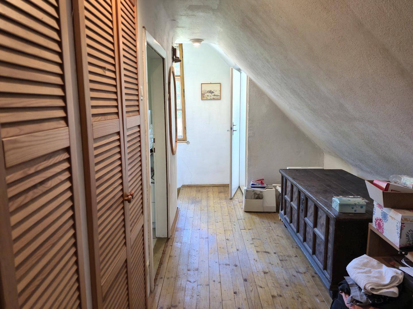 Flur im Dachgeschoss mit eingebauten Holzschränken und Holzdielenboden.