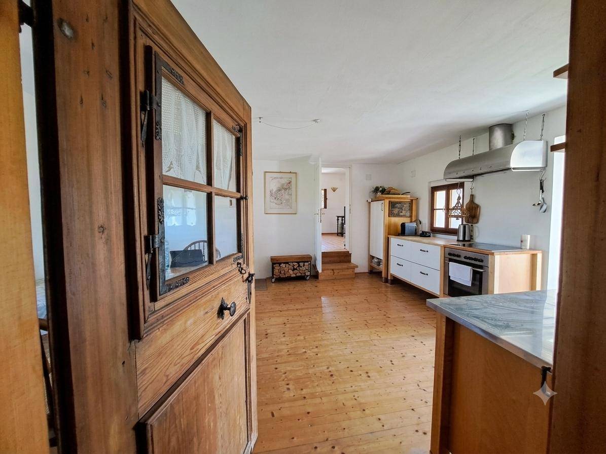 Rustikale Küche mit Holzboden, einfachen Schränken und Blick in den Flur.