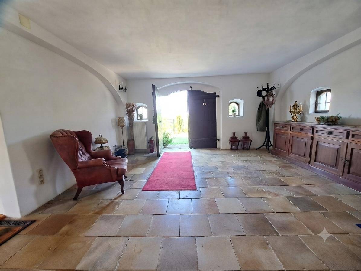Geräumiger Eingangsbereich mit rustikalen Steinplatten, Holztüren und einem roten Teppich.
