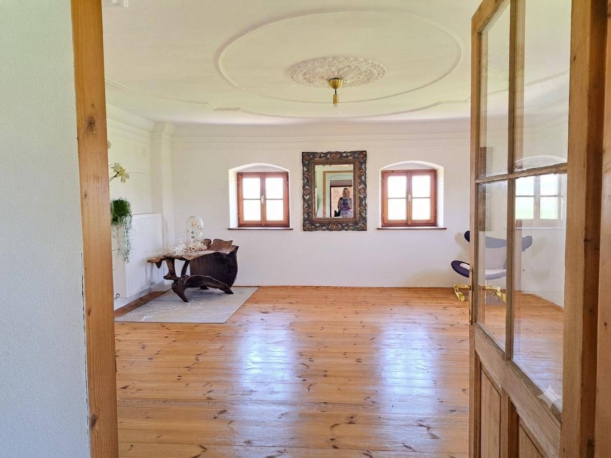 Geräumiges Wohnzimmer mit Stuckdecke, Dielenboden und traditionellen Fenstern.