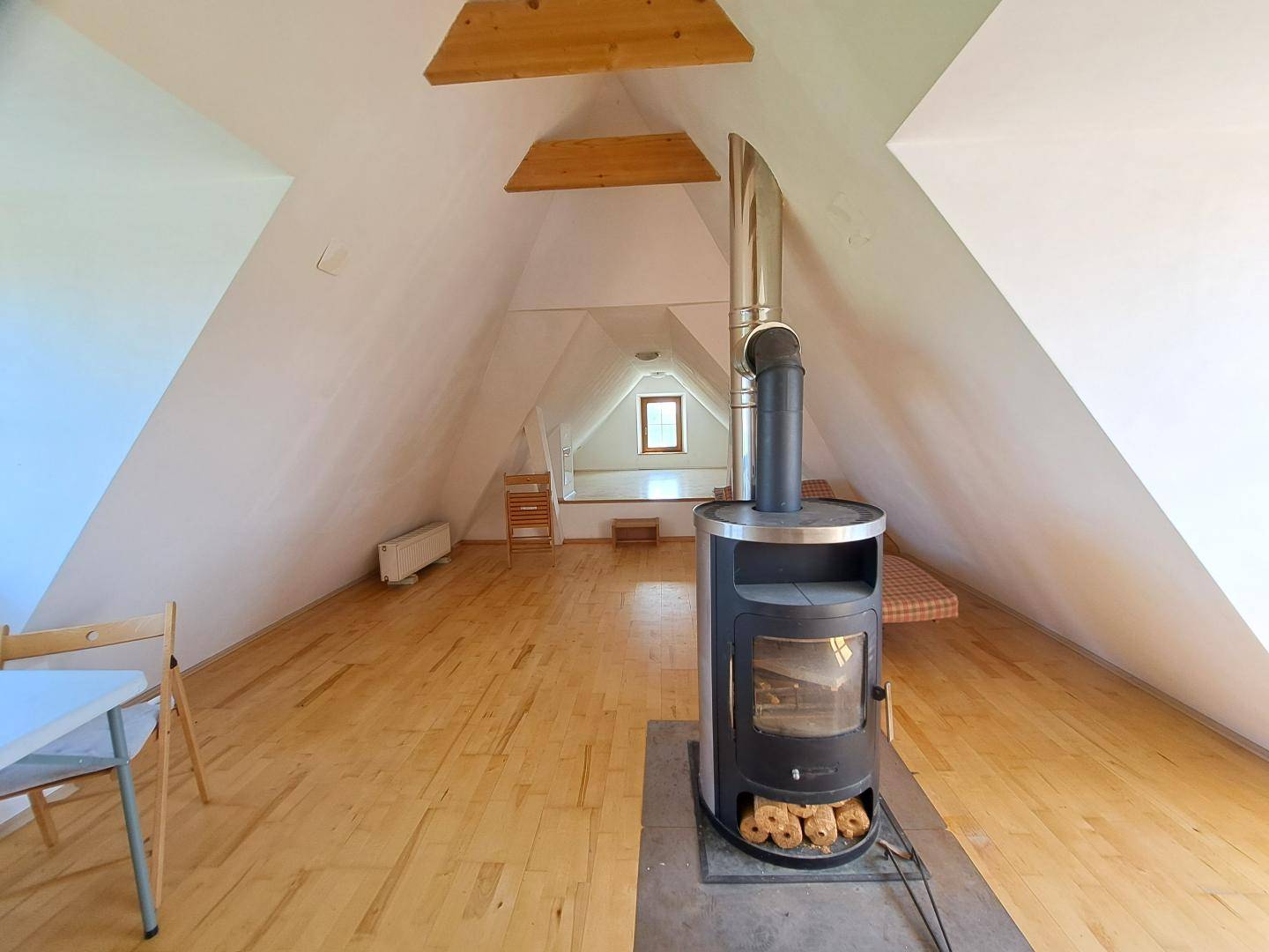 Ausgebauter Dachboden mit Holzboden, Dachschrägen und einem modernen Holzofen.