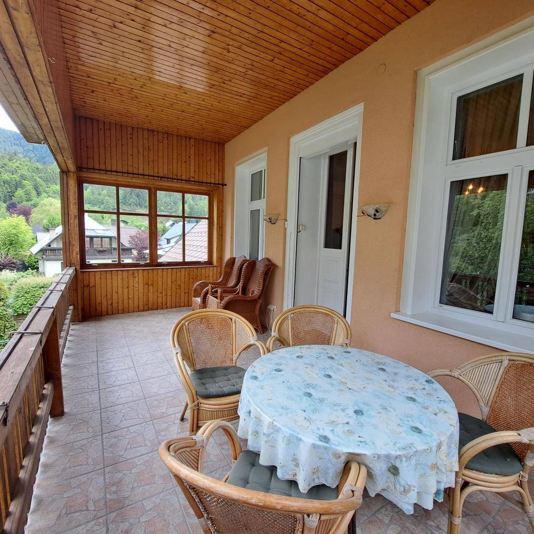 Gemütlicher Balkon mit Holzboden und Rattanmöbeln, ideal für entspannte Stunden im Freien.