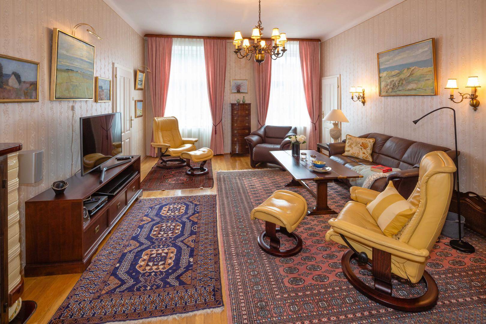 Klassisches Wohnzimmer mit bequemen Ledersofas, Teppichen und einem Fernseher, hell beleuchtet.