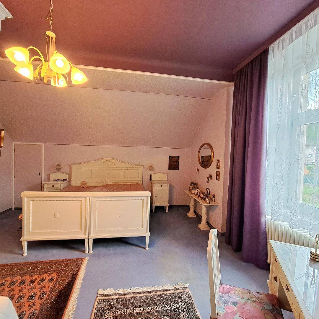 Romantisches Schlafzimmer mit weißem Himmelbett, lila Wänden und Teppichboden, sehr hell.