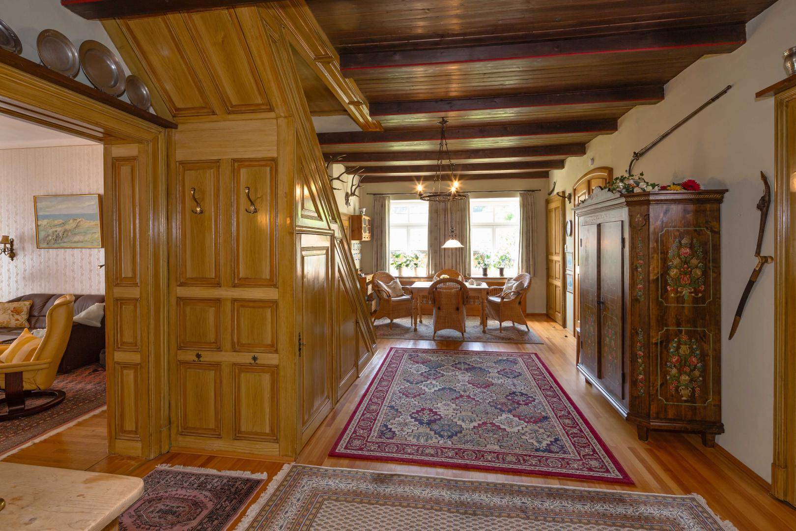 Rustikaler Flur mit Holzvertäfelung, Treppe und traditionellen Dekorationen, die zu einem Essbereich führen.