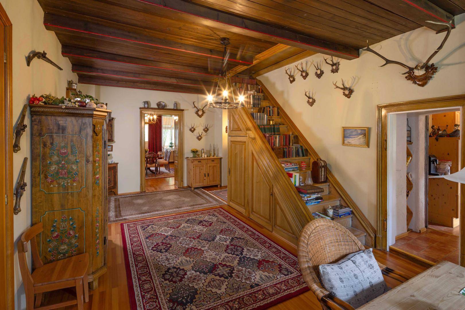 Traditioneller Eingangsbereich mit Holzdecken, Treppe und rustikalen Möbeln, geschmückt mit Hirschgeweihen.
