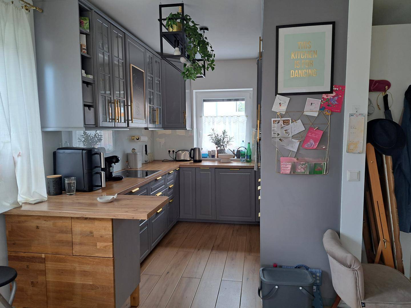 Moderne Küche mit grauen Schränken, Holzarbeitsplatten und einem Fenster für natürliches Licht.