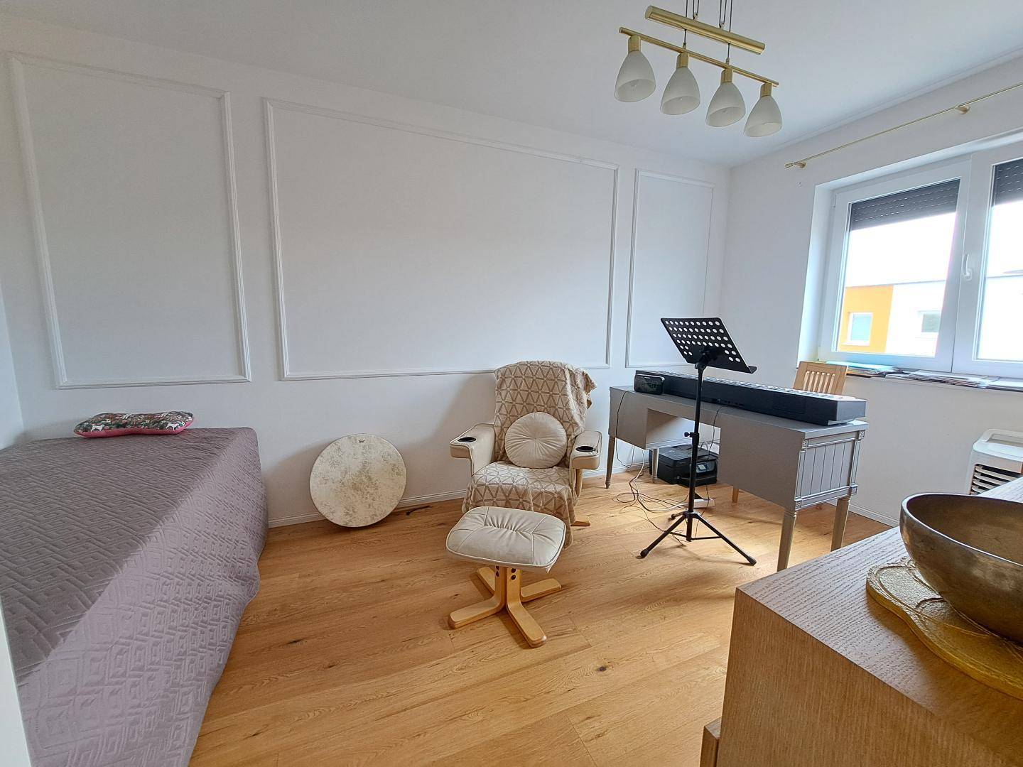 Heller Raum, eingerichtet als Büro oder Musikzimmer, mit einem Keyboard und Tagesbett.