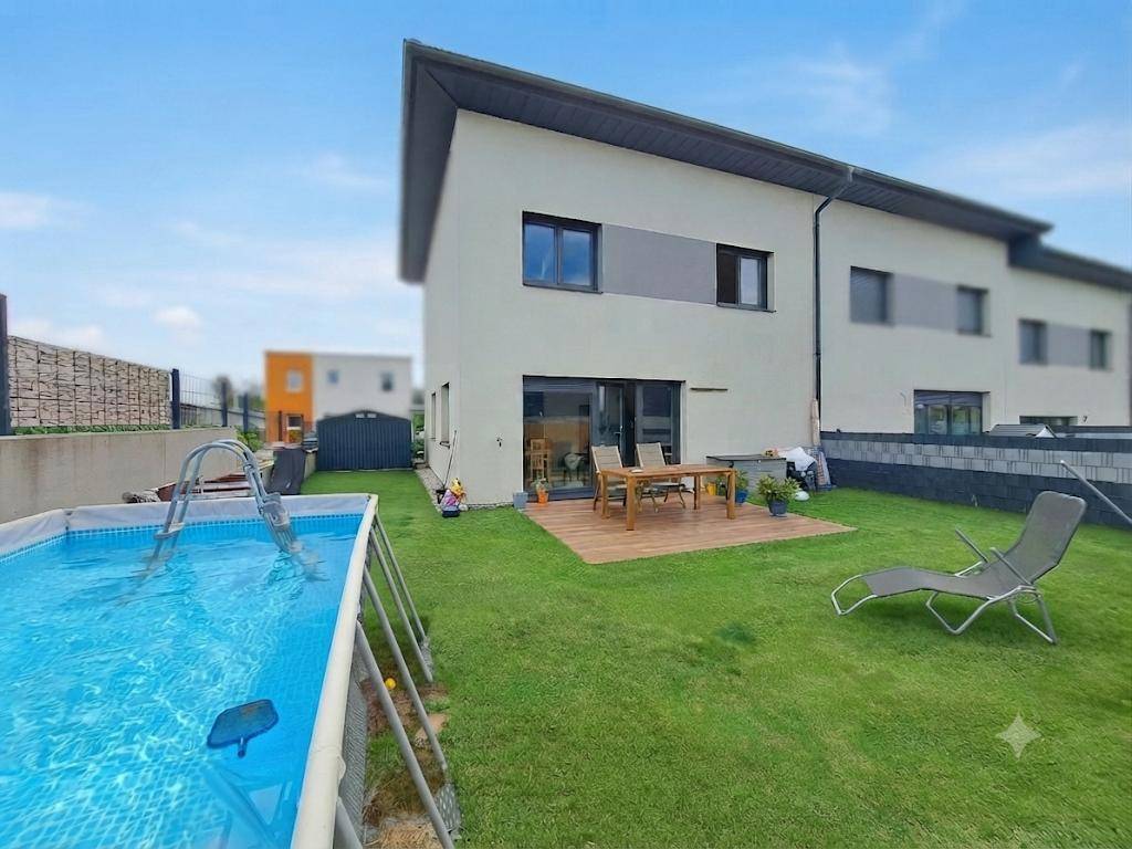 Hinterhof mit Rasenfläche, einem Aufstellpool und einer Holzterrasse mit Sitzgelegenheiten.