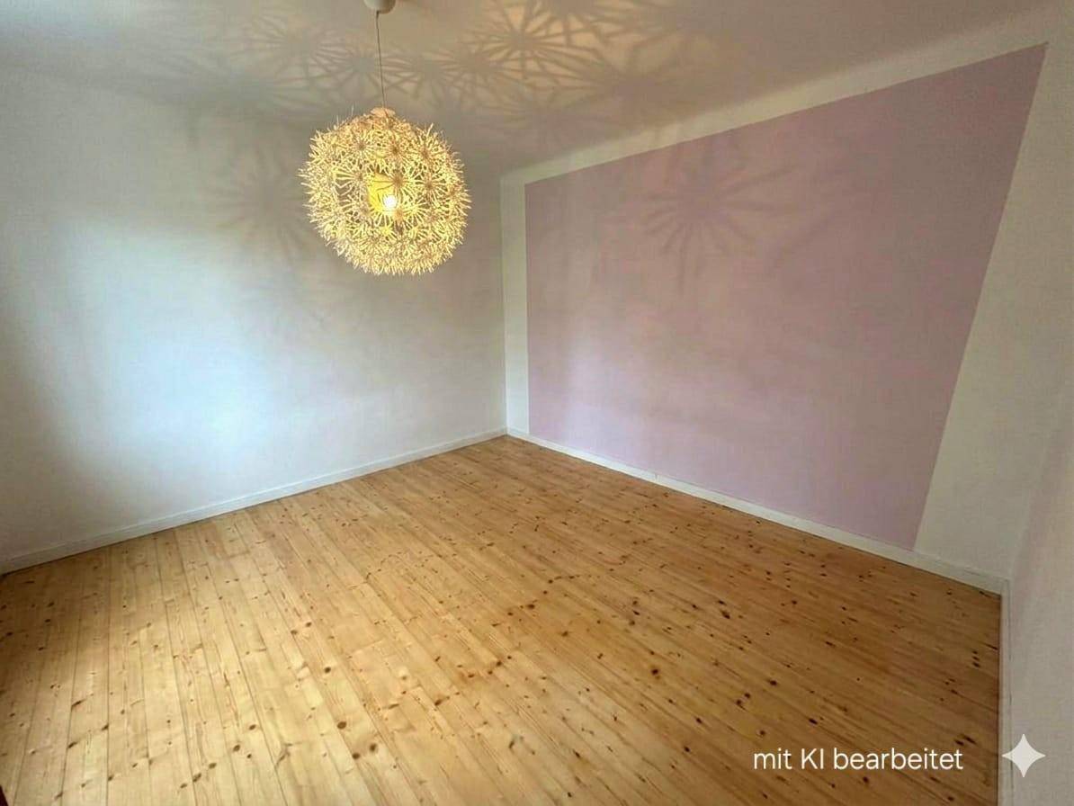 Leerer Raum mit Holzdielenboden und einer Akzentwand in zartem Rosa.