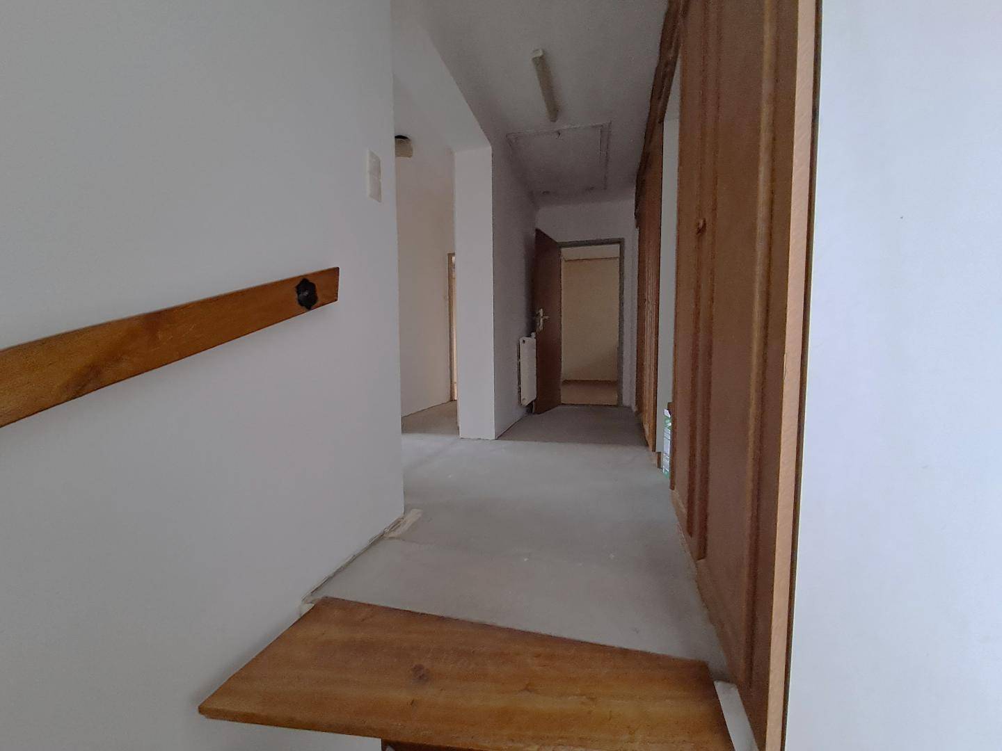 Langer Flur mit Holztüren und hellem Boden, der zu weiteren Räumen führt.