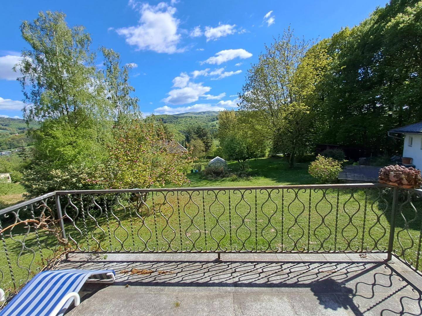 Balkon mit schmiedeeisernem Geländer und weitem Blick über die grüne Landschaft und Hügel.