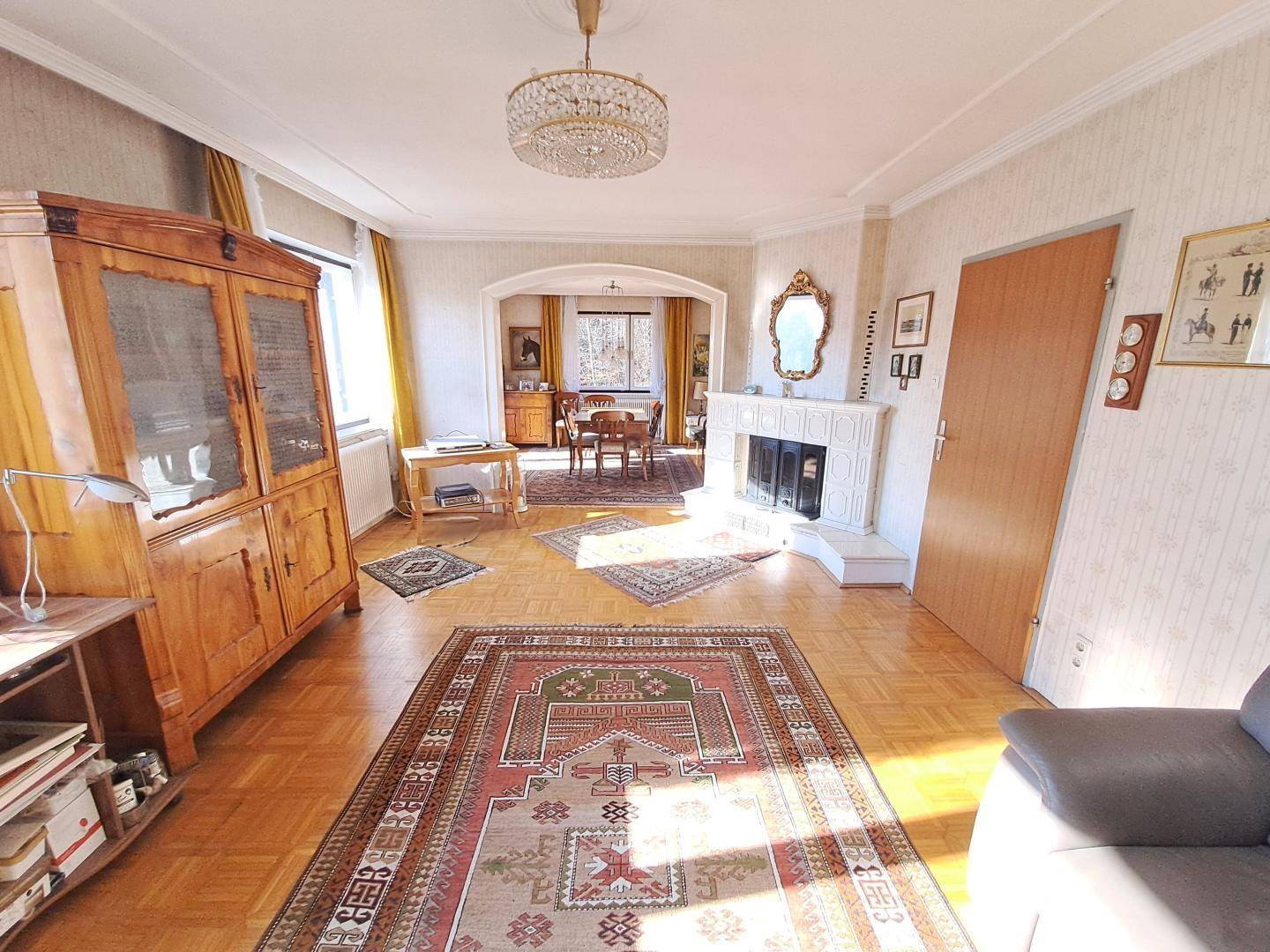 Geräumiges Wohnzimmer mit Parkettboden, Kamin und traditionellen Möbeln, offen zum Essbereich.