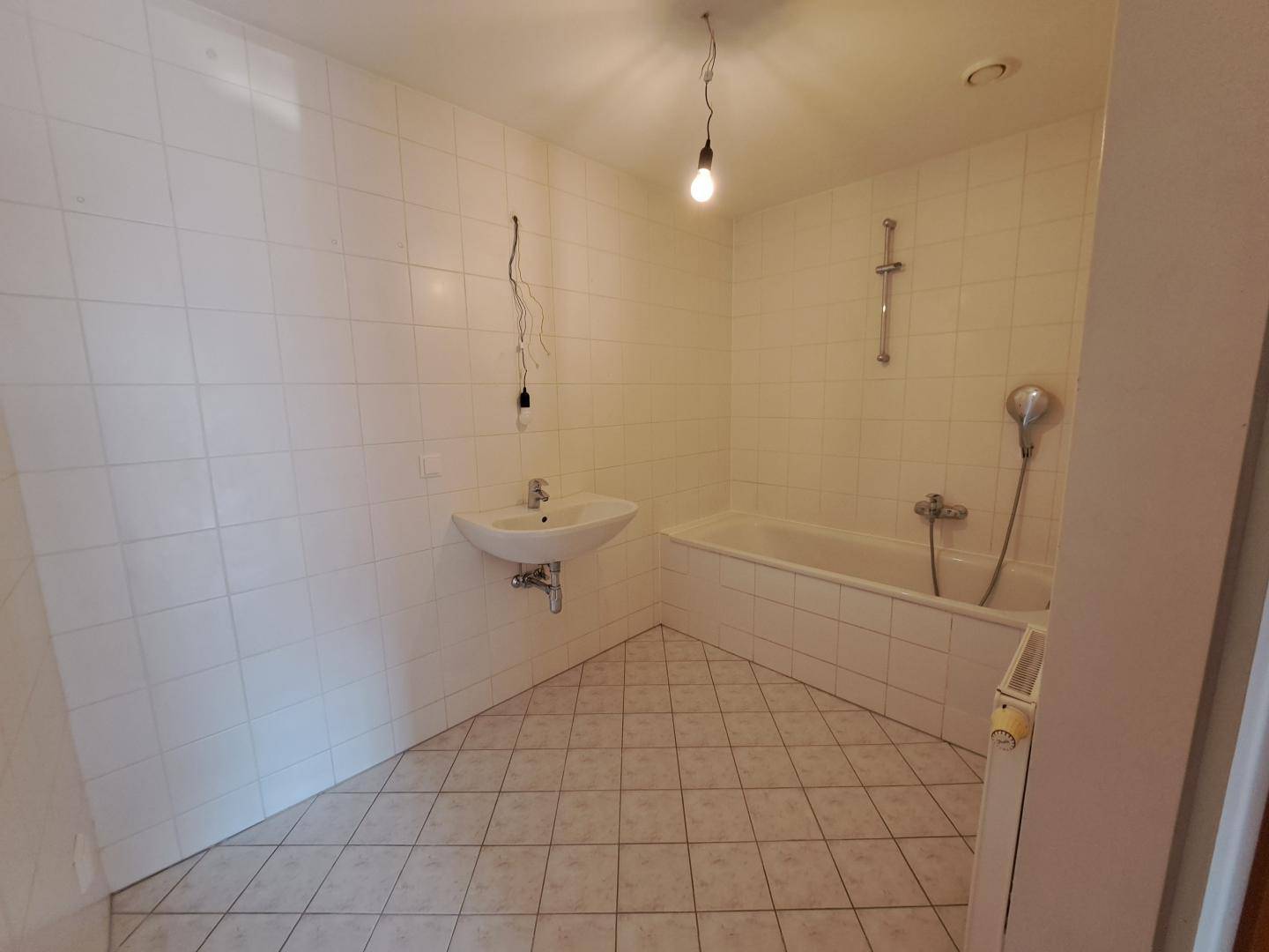 Badezimmer mit Badewanne, Waschbecken und weißen Fliesen, funktional und hell.