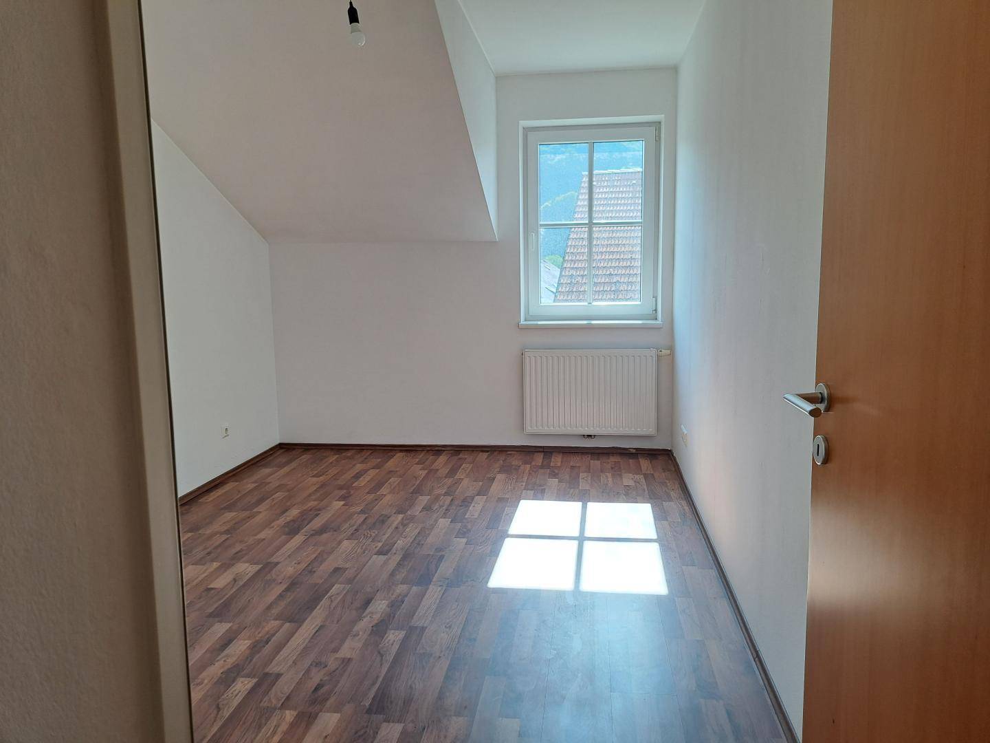 Helles Zimmer mit Holzboden und Dachschräge, ideal als Schlaf- oder Arbeitszimmer.