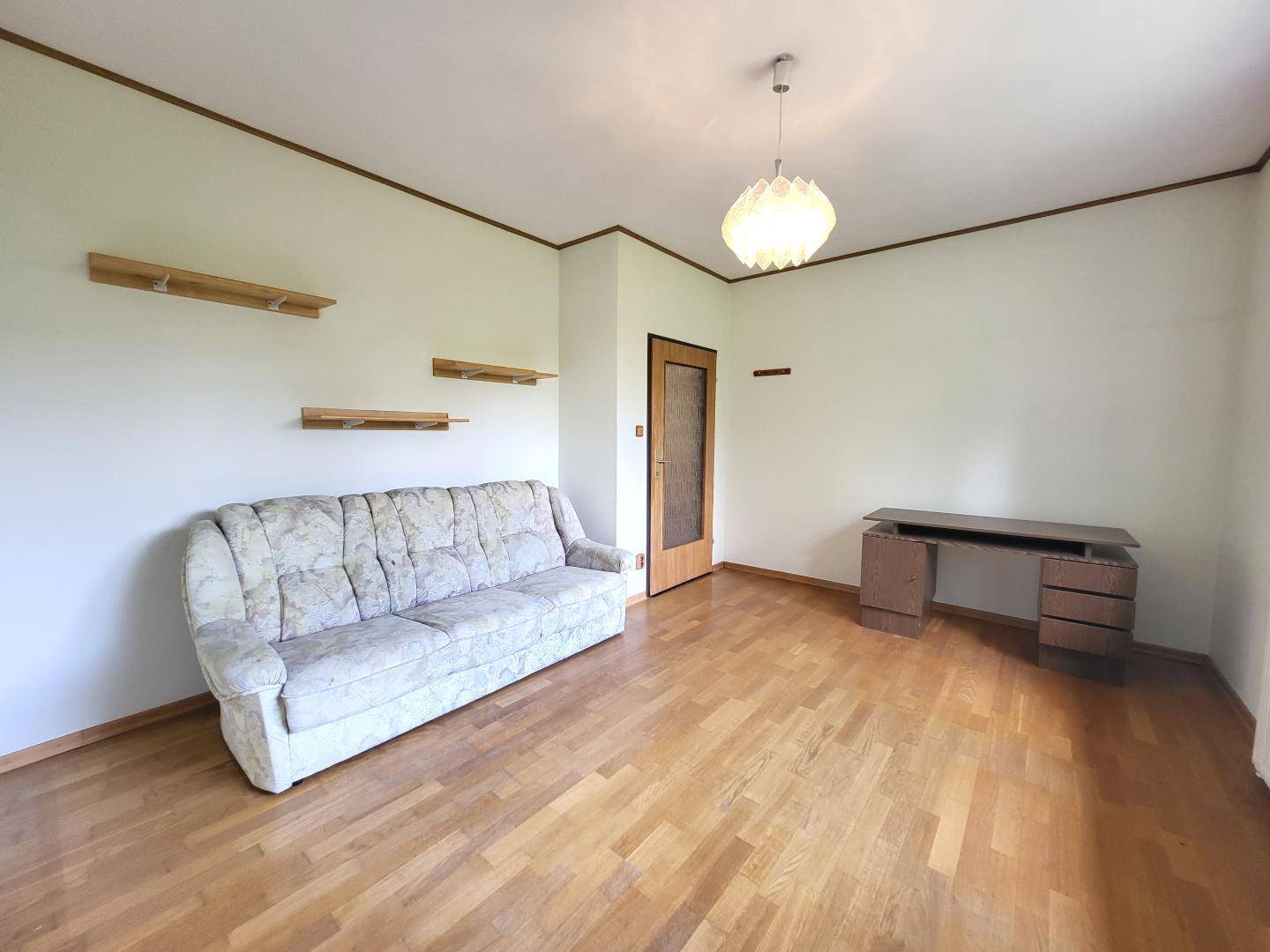 Helles Zimmer mit Parkettboden, Sofa und Schreibtisch, ideal als Büro oder Gästezimmer.