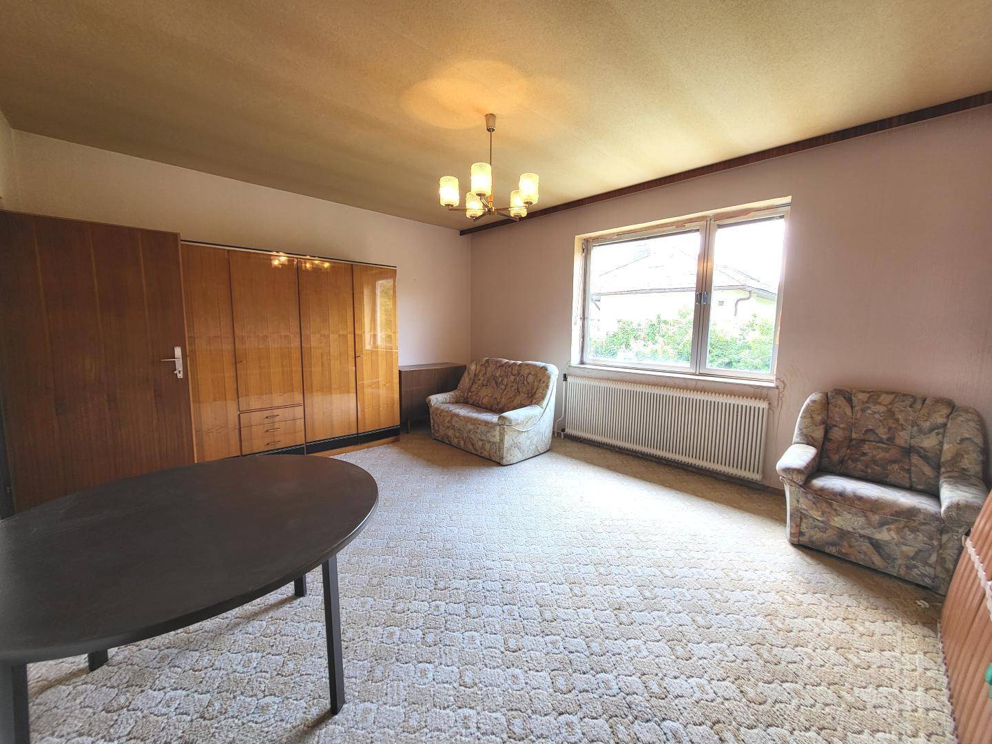 Schlafzimmer mit Teppichboden, zwei Sesseln und einem großen Kleiderschrank.