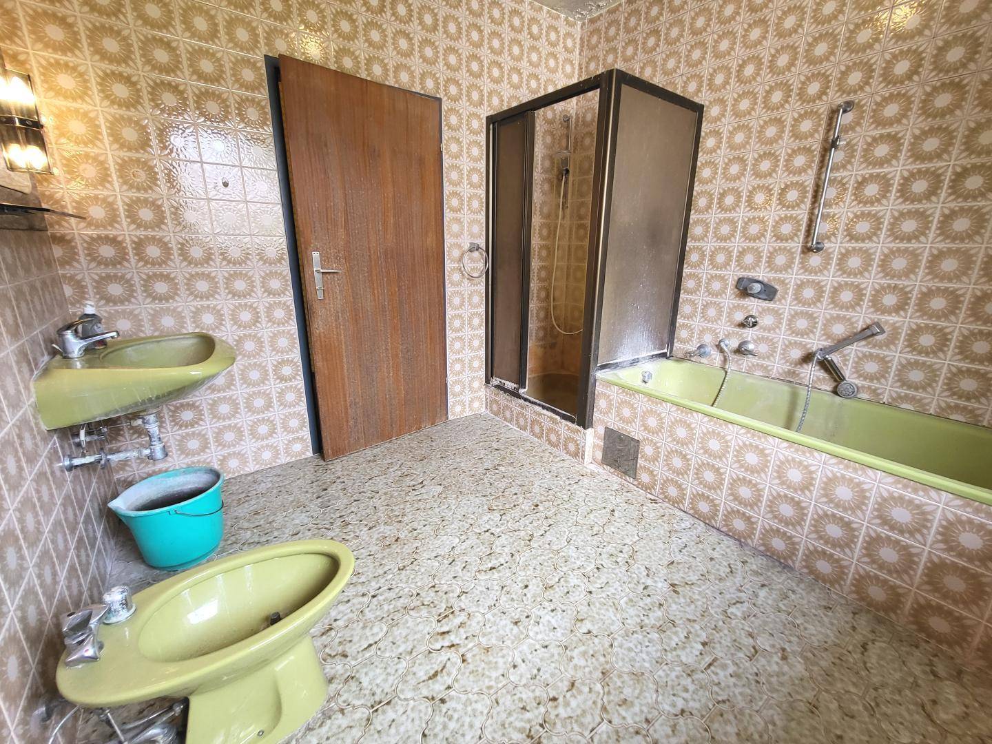 Badezimmer im 80er-Jahre-Stil mit gelben Fliesen, Badewanne, Dusche und Bidet.