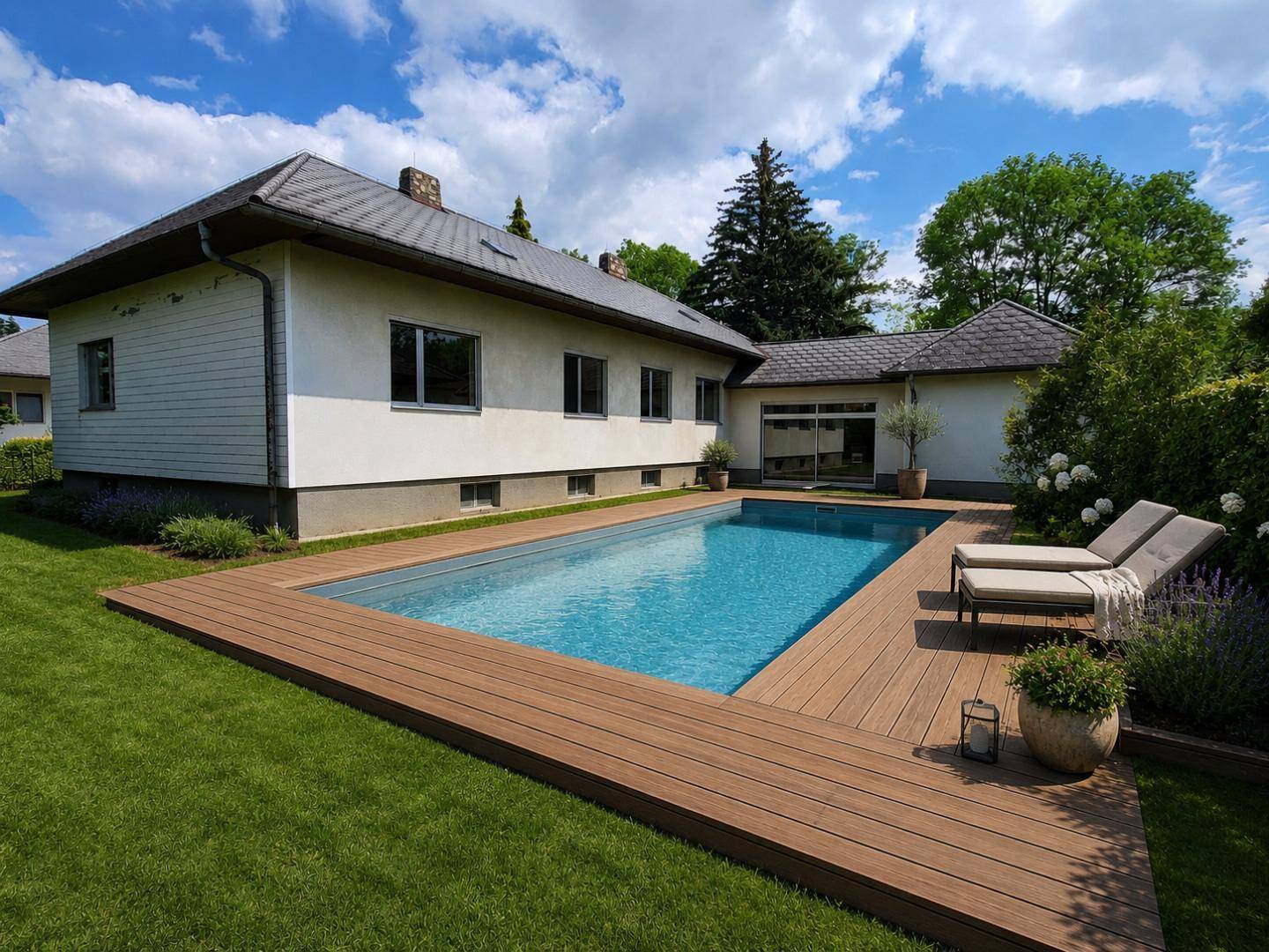 Außenbereich des Hauses mit modernem Pool, Holzdeck und Liegestühlen im grünen Garten.
