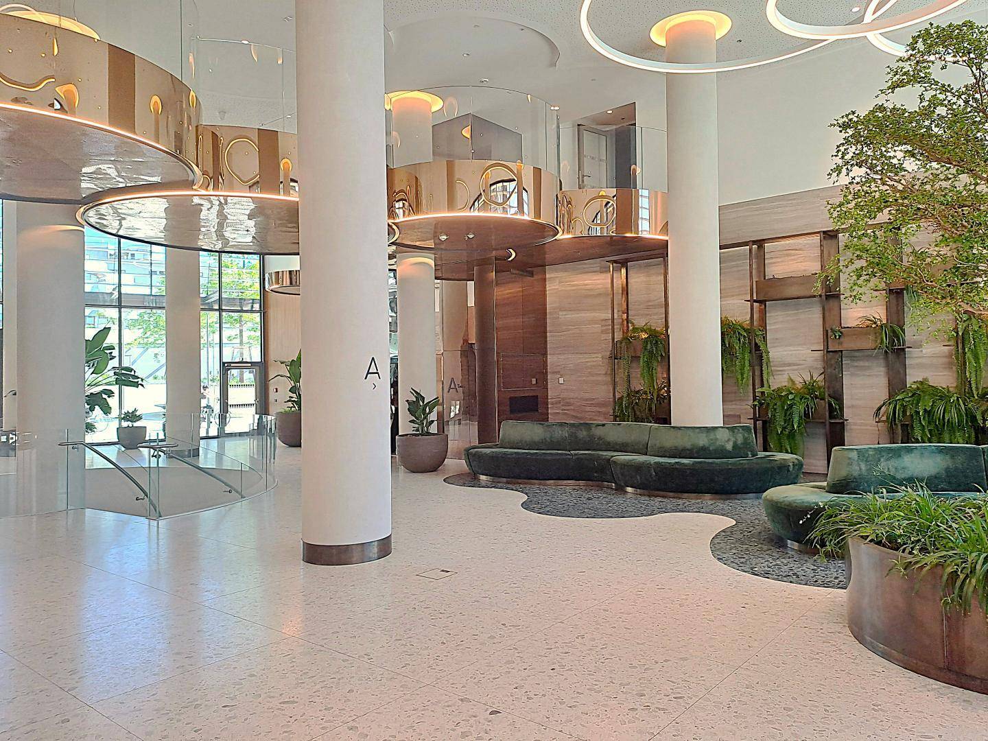 Elegante und geräumige Lobby mit hohen Decken, modernen Sitzgelegenheiten und Pflanzen.