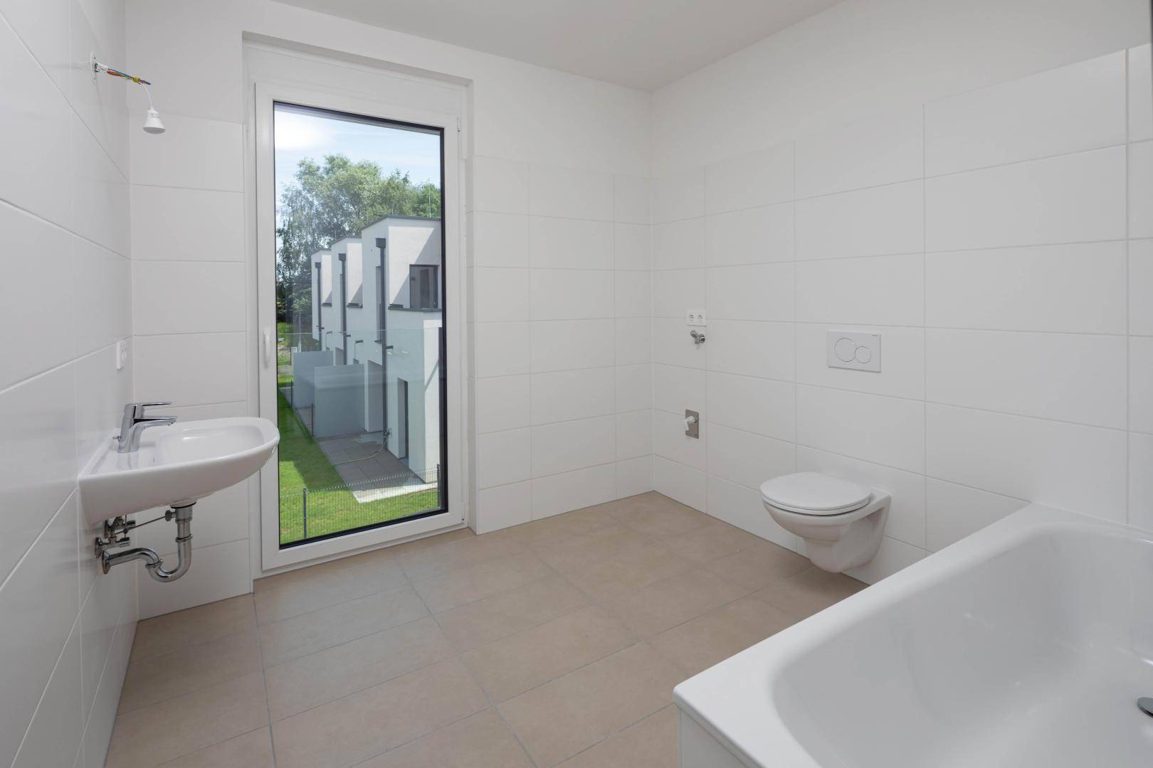 Modernes Badezimmer mit weißen Wandfliesen, Badewanne und großem Fenster.