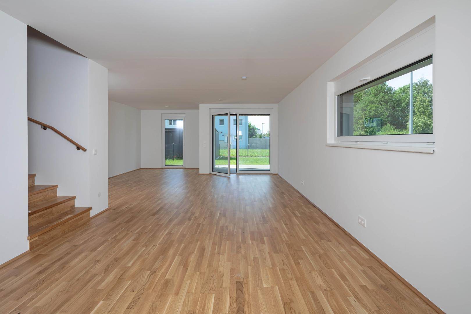 Geräumiges, helles Wohnzimmer mit Holzboden und Zugang zum Garten.