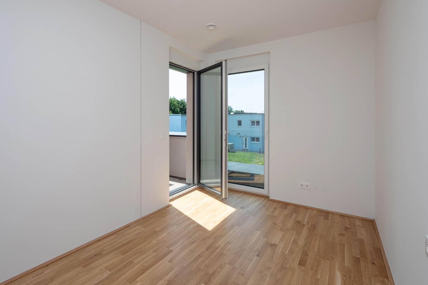 Lichtdurchflutetes Zimmer mit Eichenparkett und Zugang zu einem Balkon, bereit zur Gestaltung.