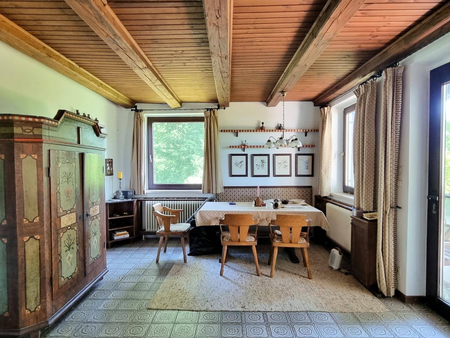 Essbereich mit rustikalen Holzbalken an der Decke, gemusterten Fliesen und traditionellen Holzmöbeln.