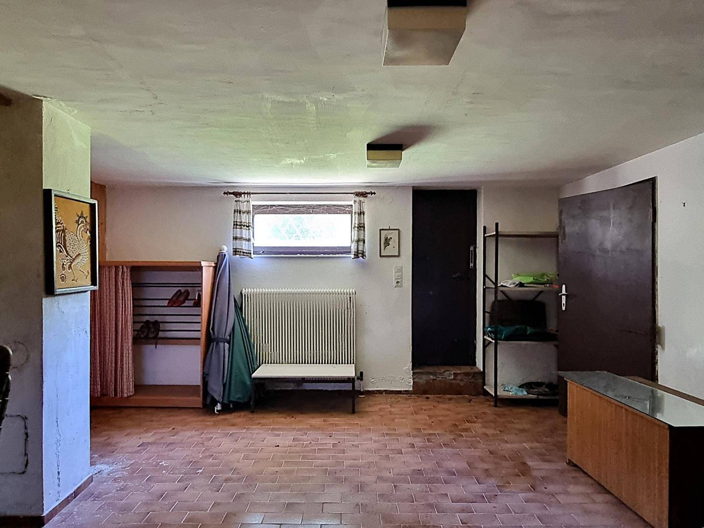 Kellerraum mit Fliesenboden, einem kleinen Fenster und praktischen Lagerregalen.