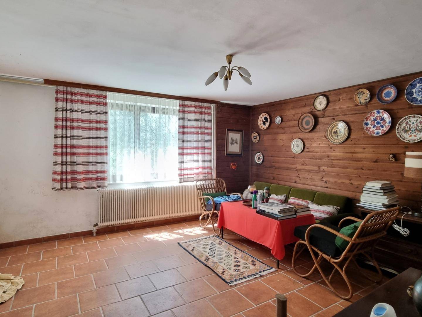 Wohn- oder Aufenthaltsraum mit holzvertäfelten Wänden, Fliesenboden und Vintage-Möbeln.