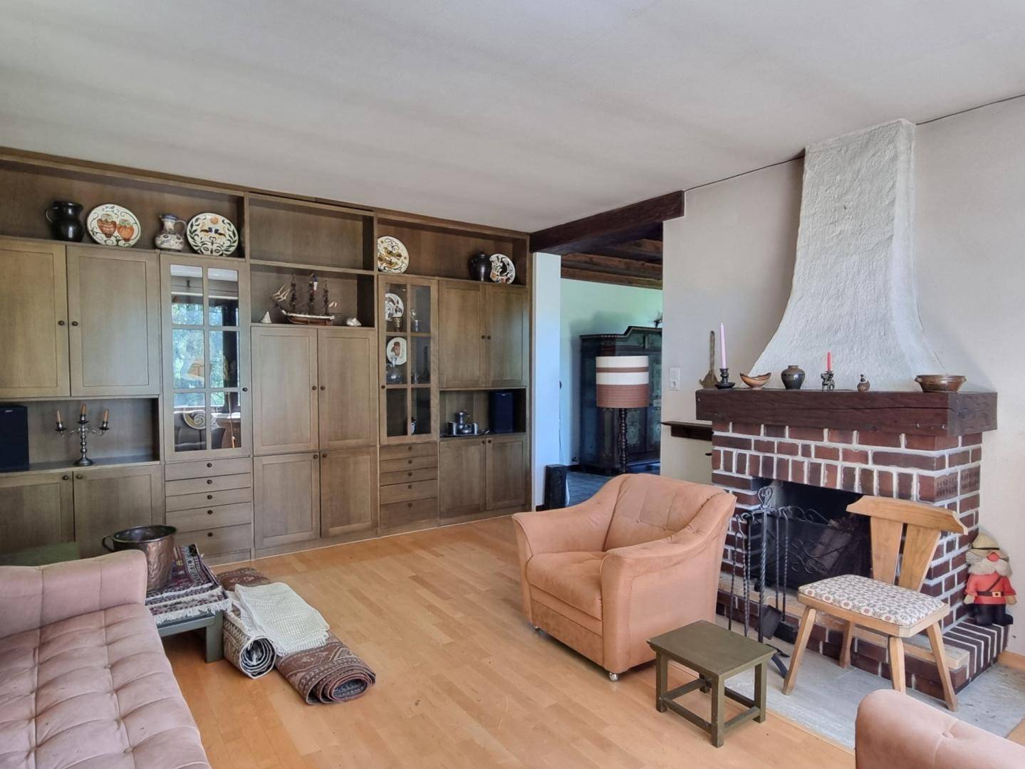 Geräumiges Wohnzimmer mit großem Einbauschrank aus Holz und einem gemauerten Kamin.