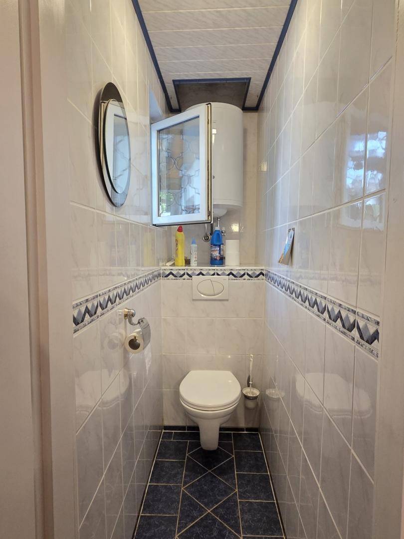 Kleines Gäste-WC mit blauen Bodenfliesen und Wand-WC.