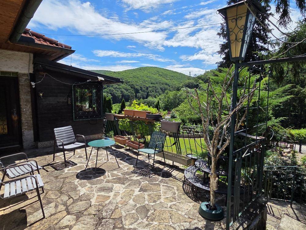 Gemütliche Steinterrasse mit Gartenmöbeln und weitem Blick über die grüne Landschaft.