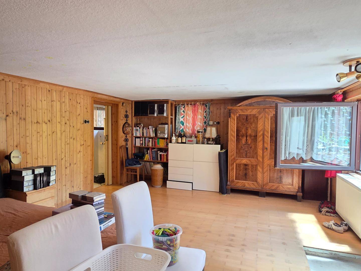 Geräumiges Zimmer mit Holzvertäfelung, Holzboden und traditionellen Möbeln.