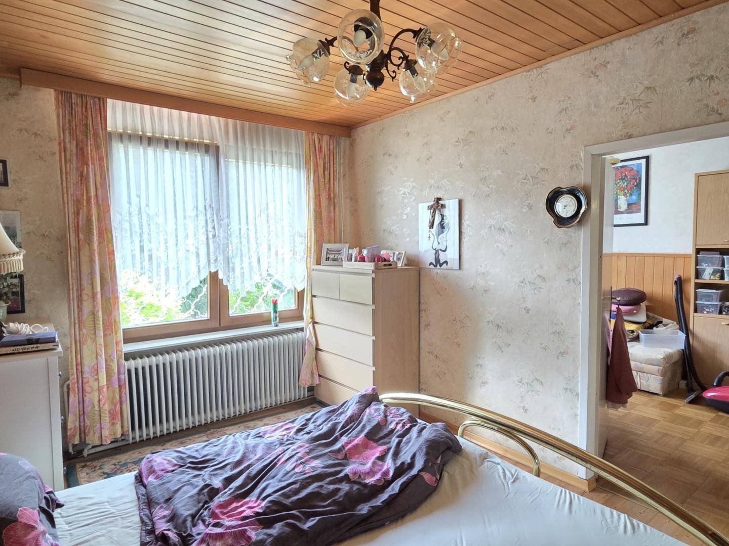 Schlafzimmer mit Holzboden, Fenster und traditioneller Einrichtung.