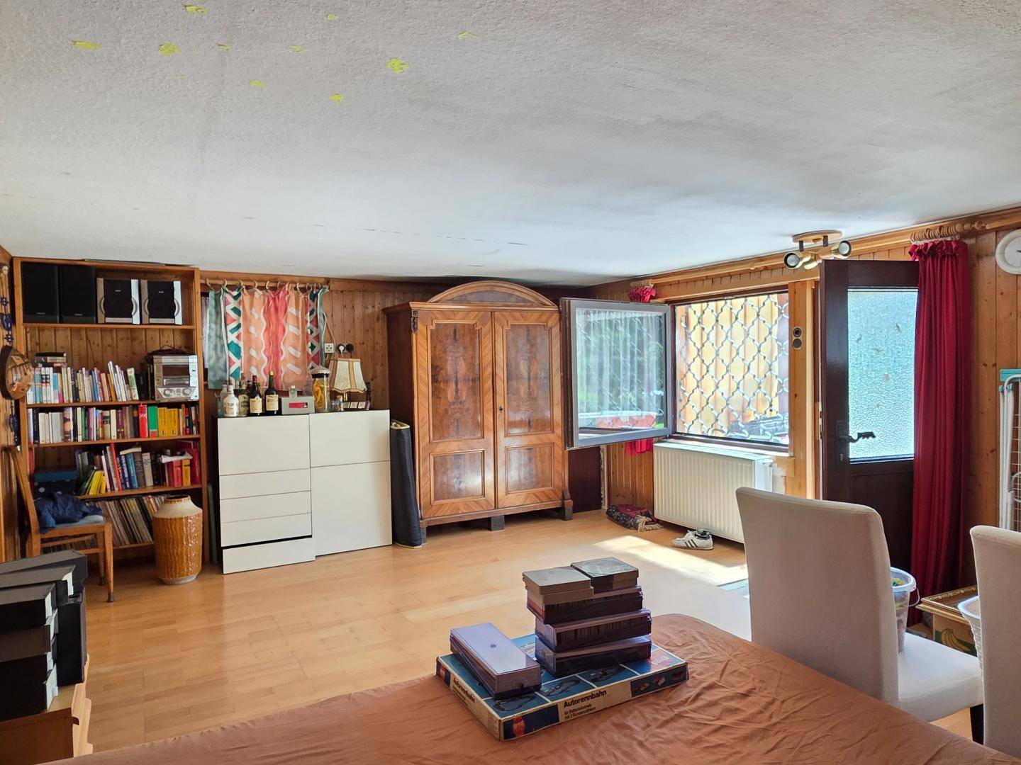 Vielseitiges Zimmer mit Holzvertäfelung, Holzboden und Bücherregal.