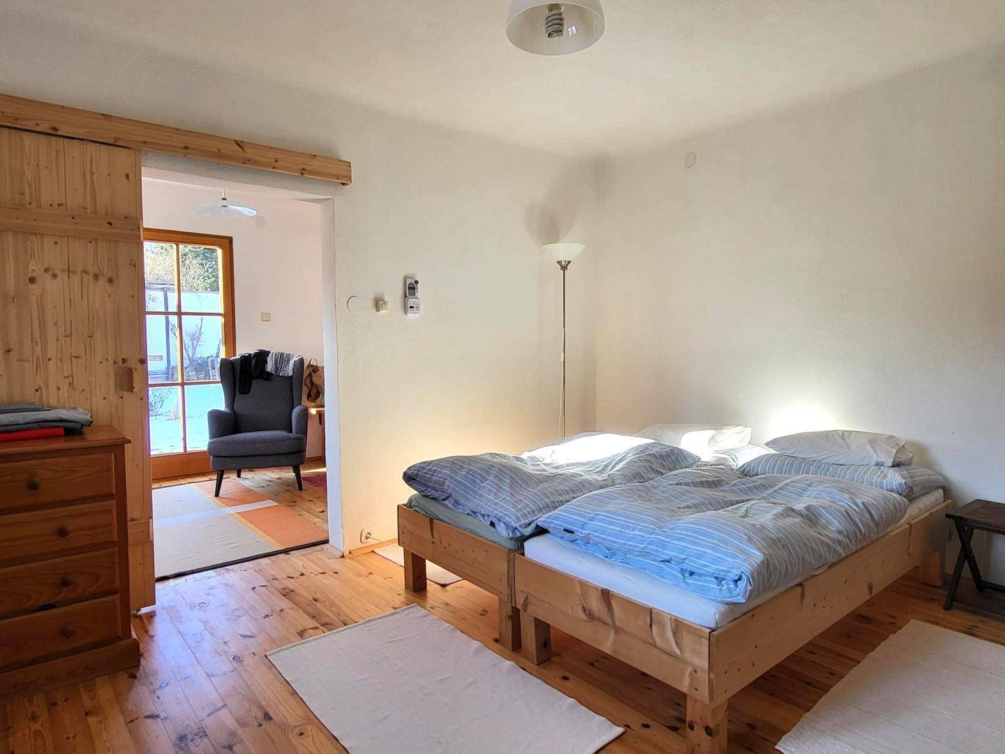 Gemütliches Schlafzimmer mit zwei Einzelbetten, Holzkommode und Zugang zu einem weiteren Raum.