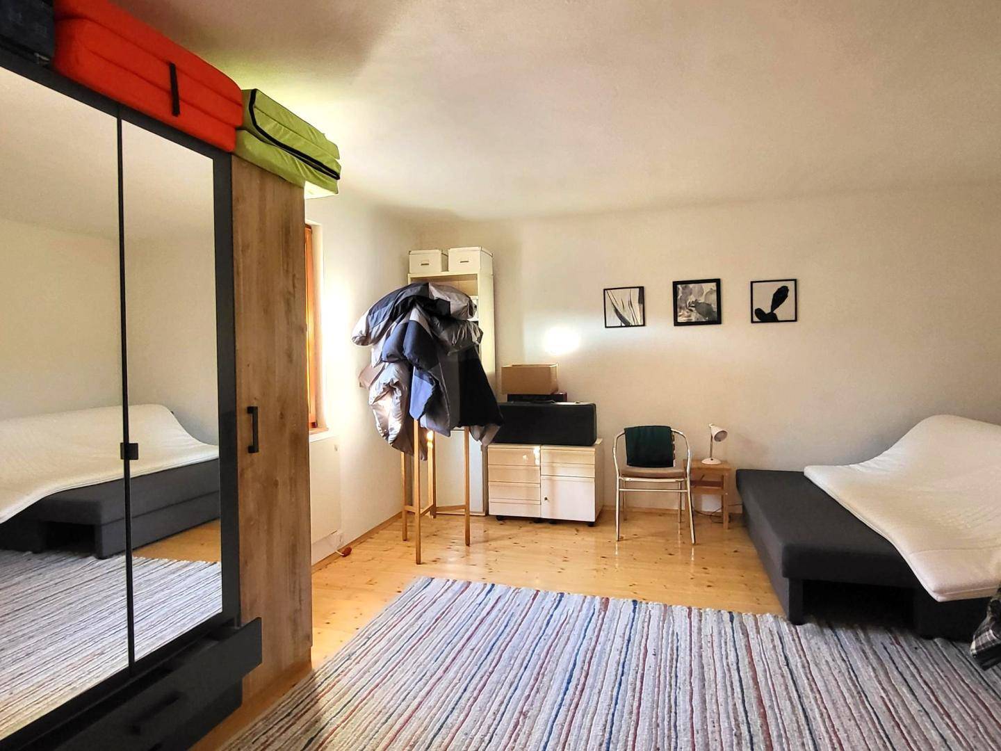 Schlafzimmer mit großem Spiegelschrank, Bett und Teppich, bietet ausreichend Stauraum.