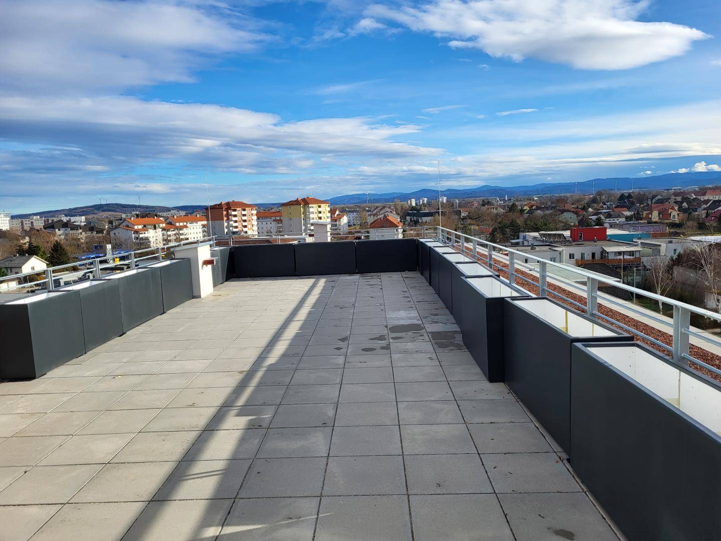 Große Dachterrasse mit weitem Blick über die Stadt und die umliegende Berglandschaft.