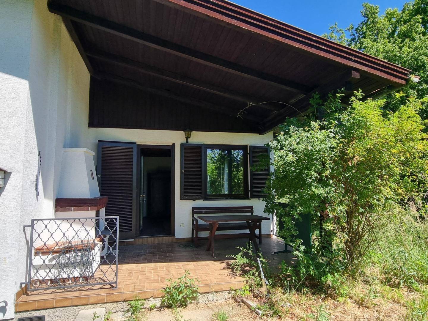 Überdachte Terrasse mit Außenkamin und Sitzbank, ideal für entspannte Stunden im Freien.