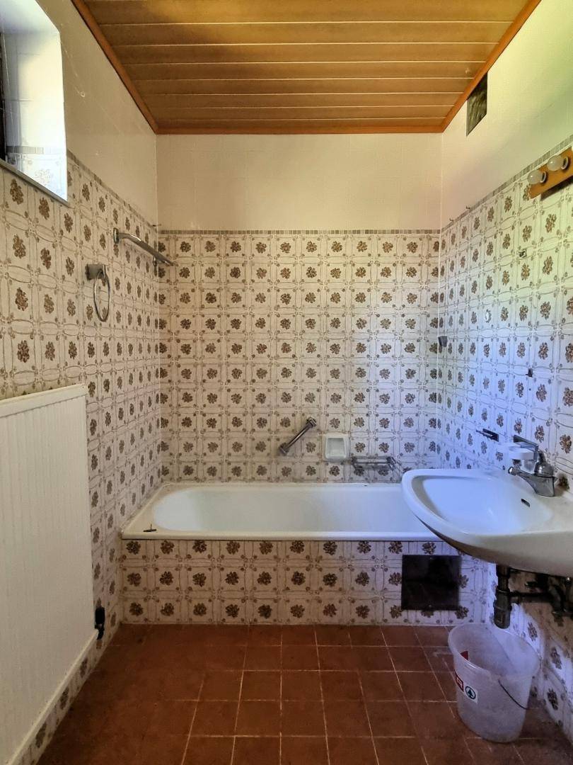 Badezimmer mit Badewanne, Waschbecken und gemusterten Wandfliesen im Vintage-Stil.