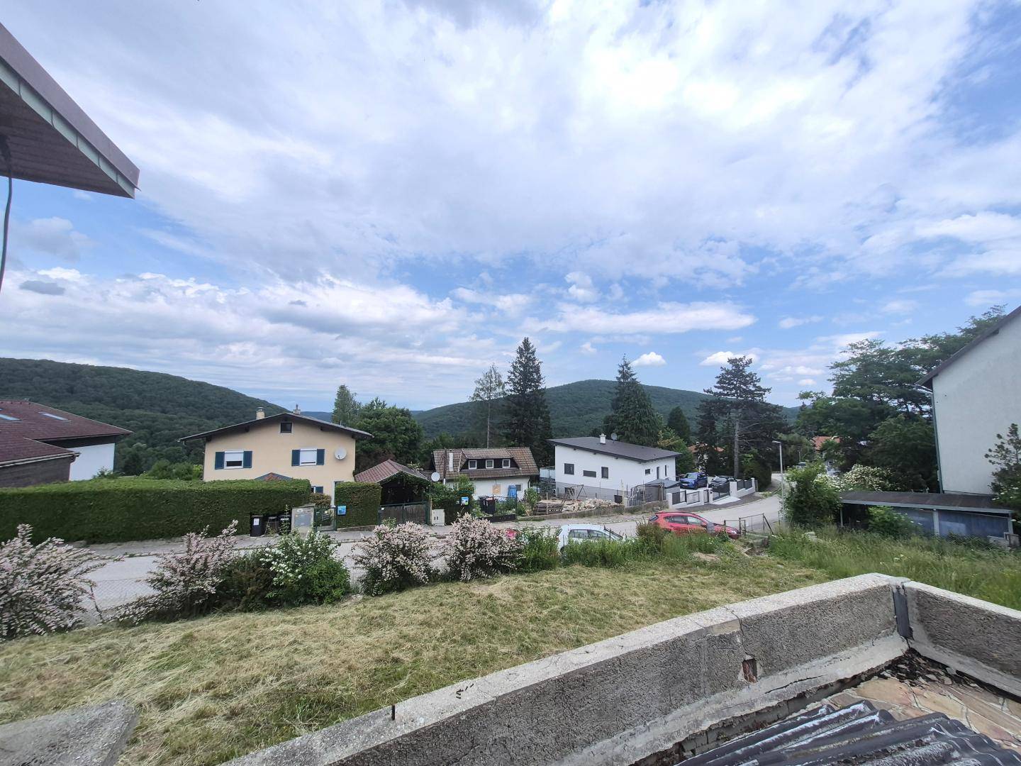 Weitläufiger Blick über die Nachbarschaft und die bewaldeten Hügel unter bewölktem Himmel.
