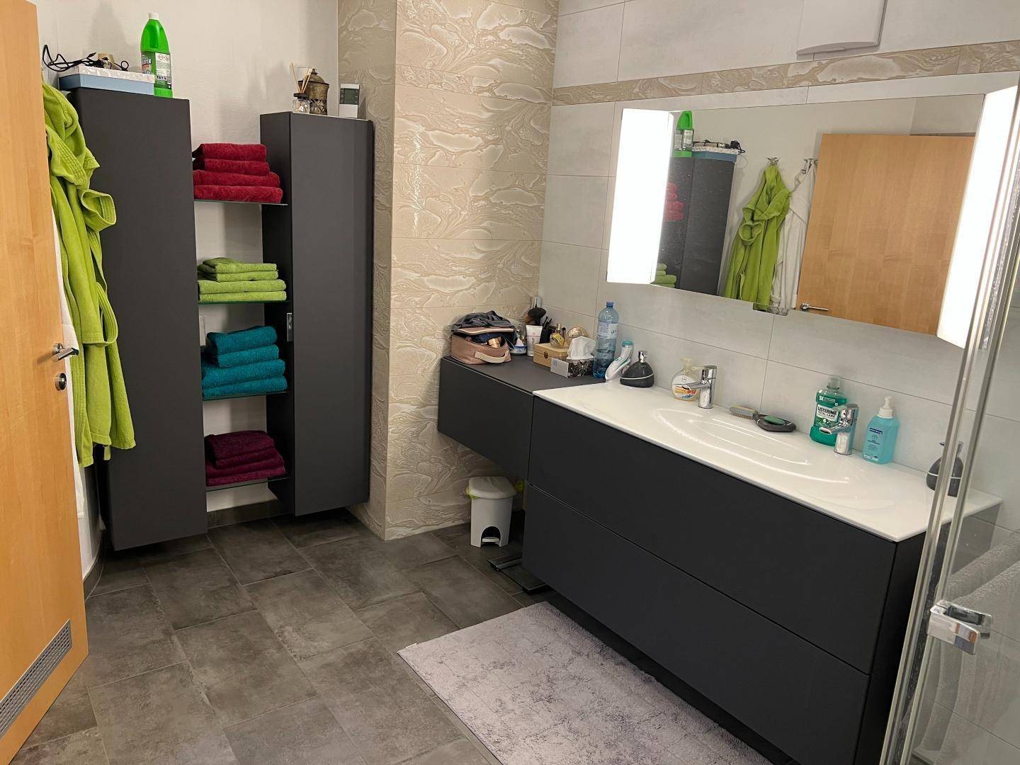 Geräumiges Badezimmer mit Doppelwaschbecken, großem Spiegel und dunklen Schränken.