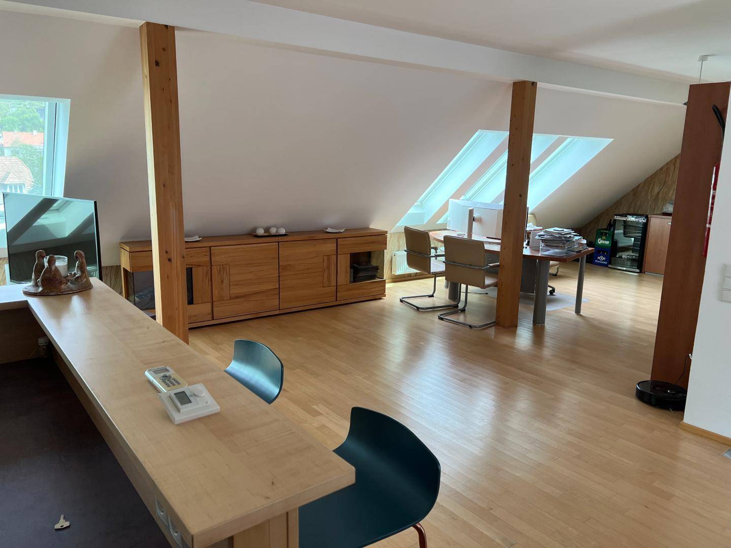 Helles Dachgeschoss-Büro mit Holzbalken, Dachfenstern und viel Arbeitsfläche.