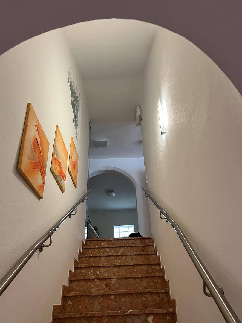 Treppenhaus mit Marmorstufen, Edelstahlgeländer und modernen Wandbildern.